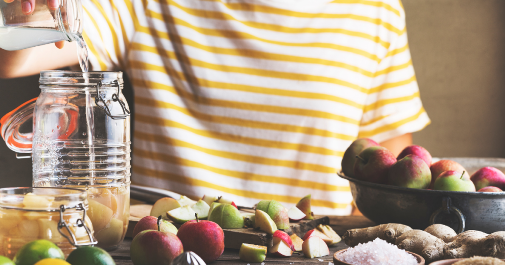 picture of a woman in a yellow striped t-shirt with apples and apple cider vinegar